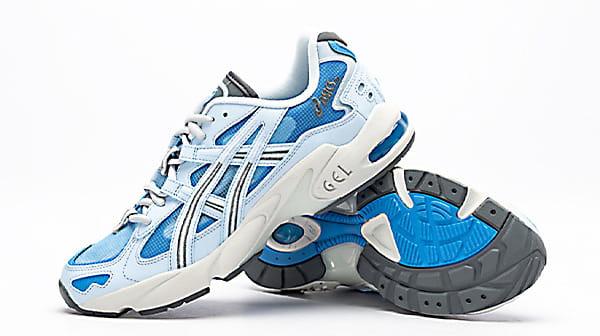 کفش ورزشی اصل اسیکس همراه با لوگوی Asics در کناره کتانی که پای چپ به زیره پای راست تکیه داده است