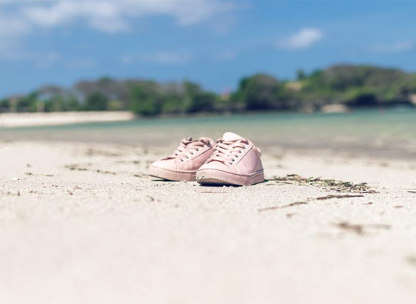 کفش اسپرت زنانه صورتی بر روی ساحل در کنار دریا در فصل گرم تابستان